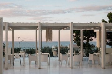 Una terrazza con un pergolato bianco sul mare, al crepuscolo.