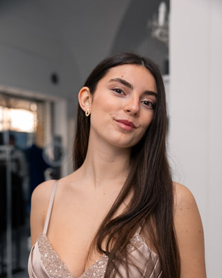 Una ragazza in abito rosa cipria con le paillettes, ritratta in un negozio di abiti.