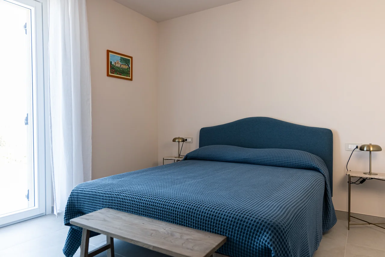 Camera luminosa con letto blu e finestra