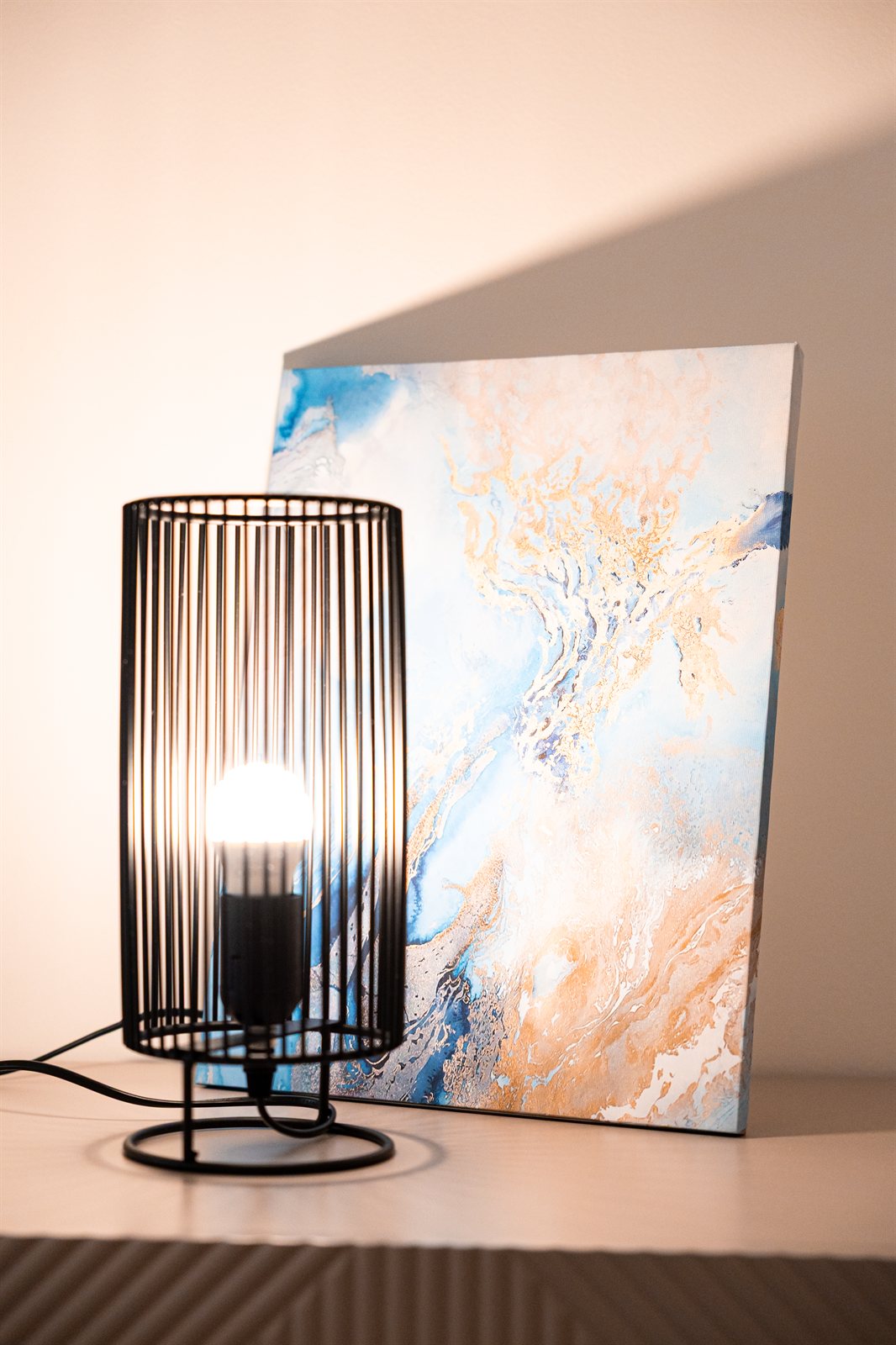 Dettaglio di una lampada e di un quadro nei toni avorio e blu